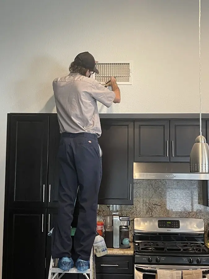 Technician inspecting an air vent during HVAC service in Billerica
